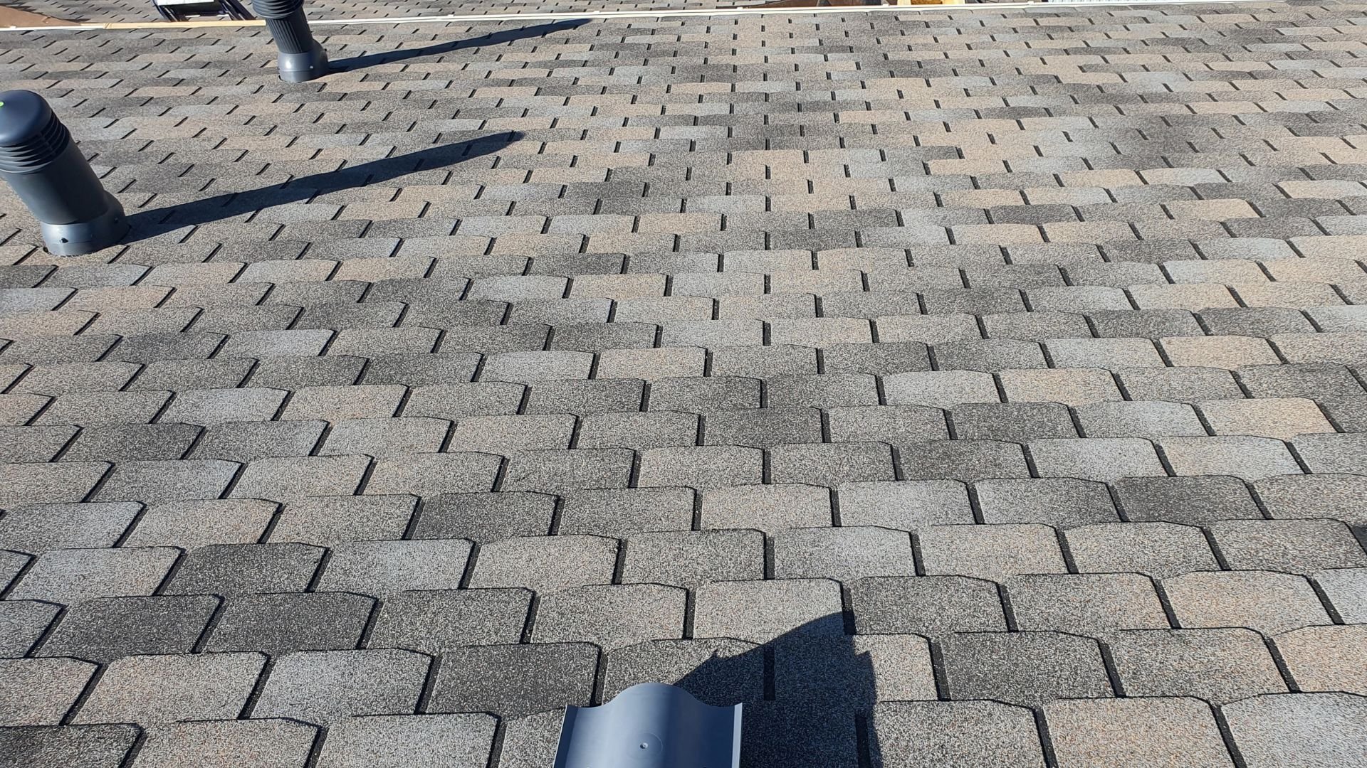 Gray asphalt shingles on a roof with black ventilation pipes
